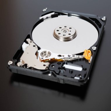 Bir bilgisayarın ya da dizüstü bilgisayarın parçalanmış bir sabit disk sürücüsü. Cihaz koyu bir mat yüzeyinde bulunuyor. Veri depolama ve korunma hakkında kare çizim. Bilgisayar donanımı ve donanımı