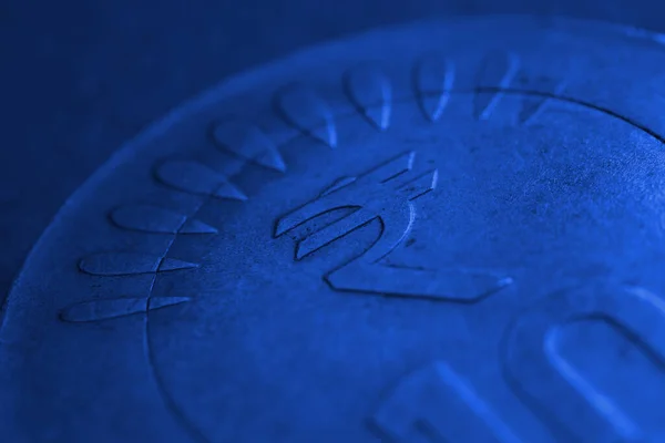 Translation: rupee. Fragment of Indian 10 rupee coin with a national currency symbol close-up. The very dark blue background or backdrop. Money, banking and finance of India. Macro
