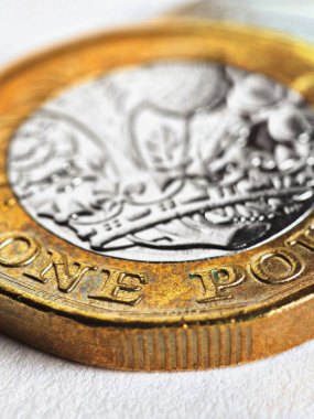 İngiliz 1 pound sterlin madeni parası beyaz bir yüzeyde yatıyor. İngiltere 'de ekonomi, para ve bankacılık hakkında dikey illüstrasyon. Nominal değere odaklan. İngiliz para birimi. Makro