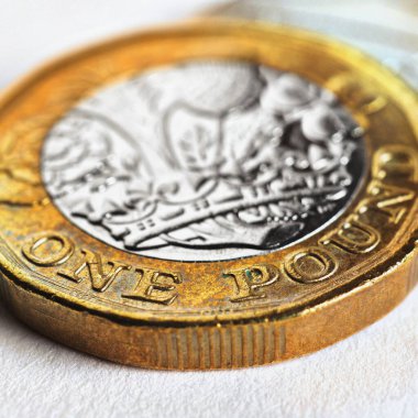 İngiliz 1 pound sterlin madeni parası beyaz bir yüzeyde yatıyor. İngiltere 'de ekonomi, para ve bankacılık hakkında kare çizimler. Nominal değere odaklan. İngiliz para birimi. Makro