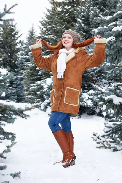 Muchacha mostrar pelo en el parque de invierno en el día. Abeto con nieve. Pelirroja mujer longitud completa . — Foto de Stock