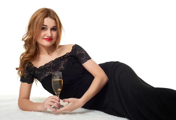 Chica con copa de champán acostado en piel, con un vestido negro . — Foto de Stock