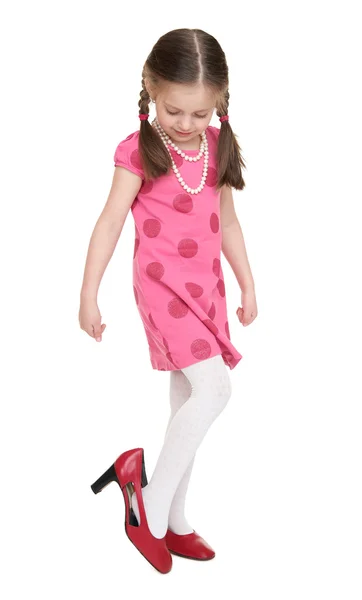 Meisje kind in rode jurk kijk op schoenen met hoge hakken — Stockfoto