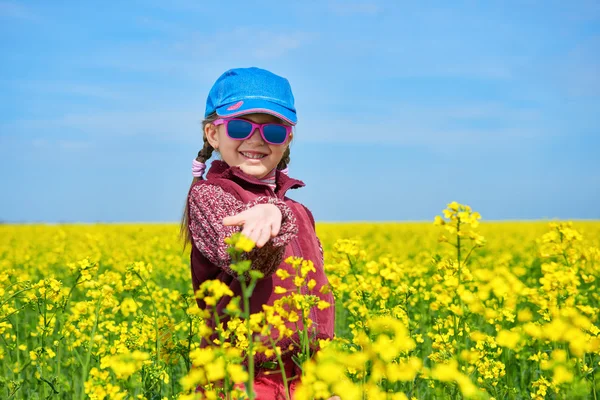 Dívek v řepkovém poli s jasně žlutými květy, jarní krajina — Stock fotografie