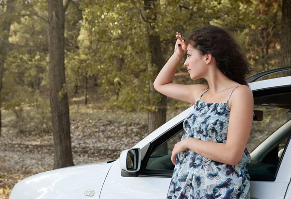 Chica de pie en el camino del campo cerca de auto mirar a la distancia, grandes árboles altos, temporada de verano — Foto de Stock