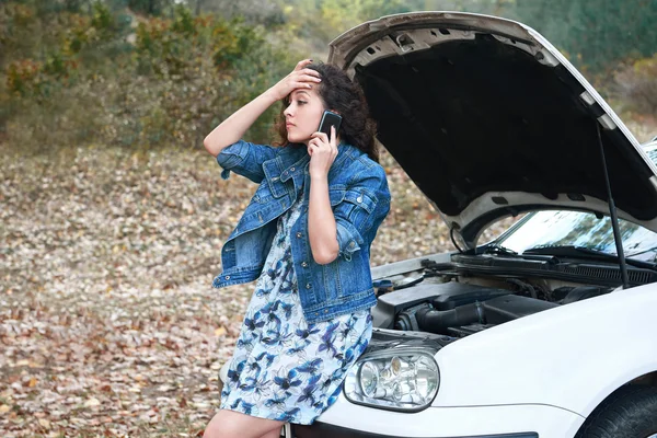 Chica con un coche roto, abrir la capucha, pedir ayuda — Foto de Stock