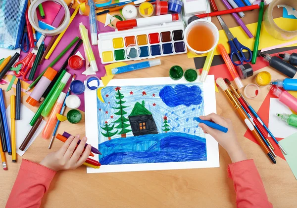Child drawing christmas night in forest with house , top view hands with pencil painting picture on paper, artwork workplace — Stock Photo, Image