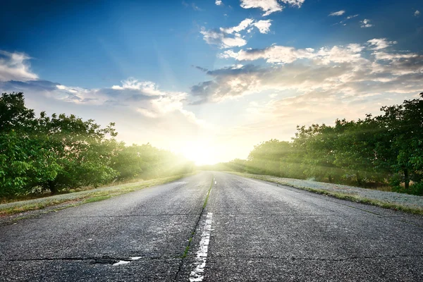 Carretera carretera al atardecer, viaje y concepto de transporte, cielo nublado y sol en el horizonte, hermoso paisaje de verano — Foto de Stock
