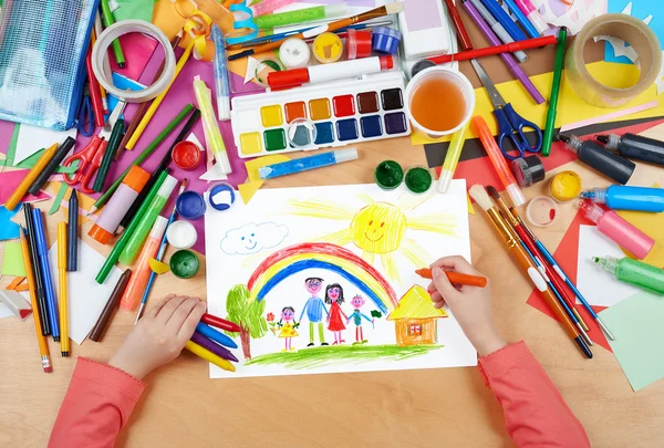 Família no prado com desenho do arco-íris e da criança da casa, as mãos da vista superior com quadro da pintura do lápis no papel, local de trabalho da arte — Fotografia de Stock