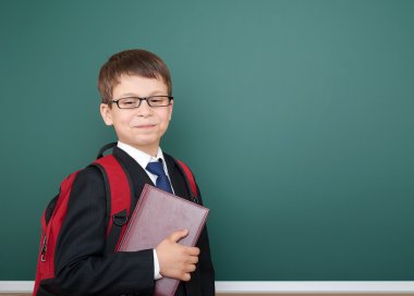 kırmızı sırt çantası ve kitap, eğitim kavramı ile yeşil tebeşir arka plan üzerinde siyah takım elbise li okul çocuk portresi