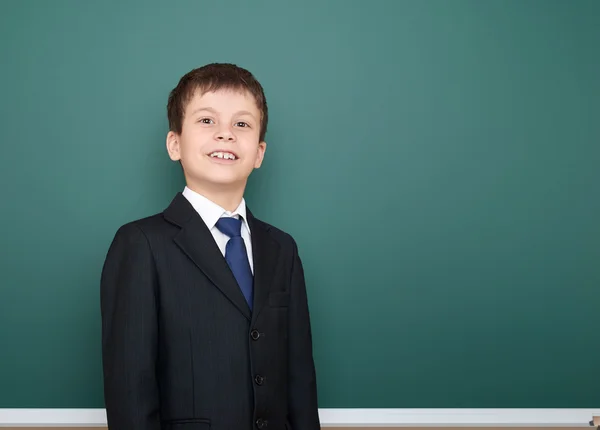 Happy successfull school boy in black suit portrait on green chalkboard background, education concept — Stock Photo, Image
