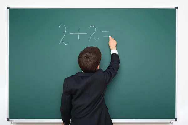 School boy decides examples math on chalkboard background, education exam concept — Stock Photo, Image