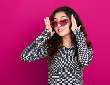 genç kadın güzel portre, poz pembe bir arka plan, uzun kıvırcık saç, kalp şeklinde, glamour kavramı güneş gözlüğü