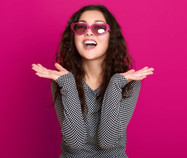 genç kadın güzel portre, poz pembe bir arka plan, uzun kıvırcık saç, kalp şeklinde, glamour kavramı güneş gözlüğü