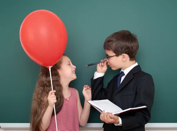 School boy and girl child with balloon on chalkboard background having fun — Stock Photo, Image