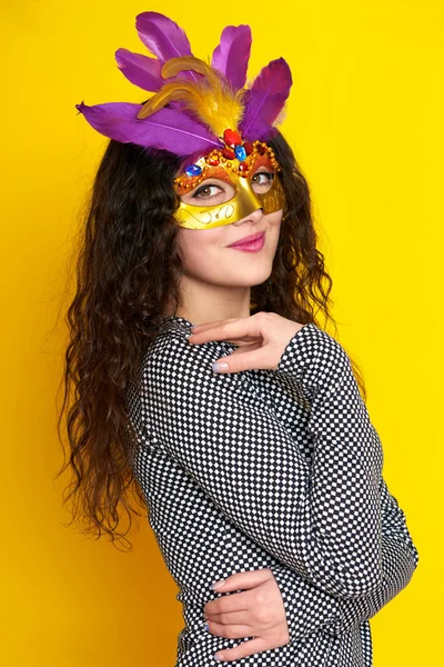 Woman in carnival mask with feather, beautiful girl portrait on yellow color background, long curly hair — Stock Photo, Image