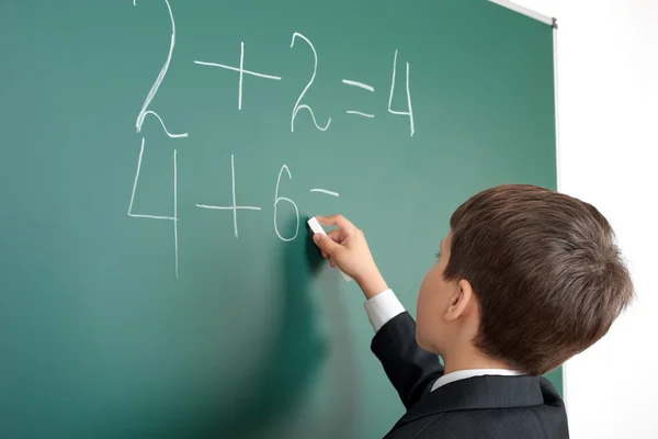 Écolier décide exemples mathématiques sur fond tableau, concept d'examen d'éducation — Photo