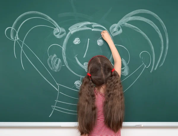 Colegiala niño en vestido de rayas rojas dibujo hombre feliz en el fondo de pizarra verde, concepto de vacaciones de la escuela de verano —  Fotos de Stock