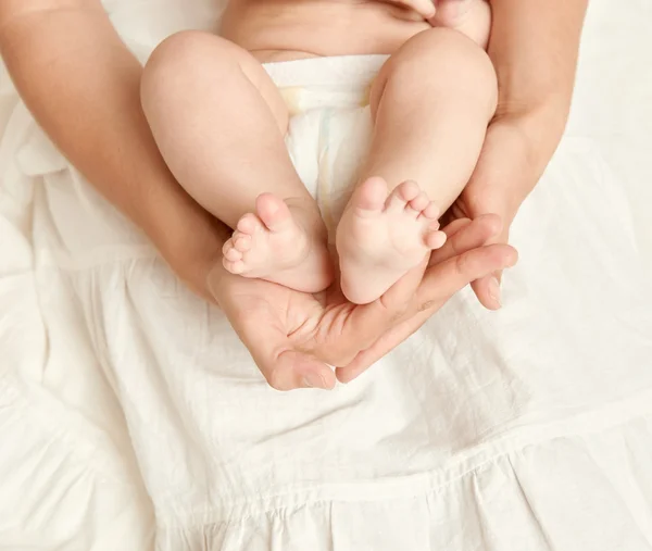 Babyfüße in der Hand der Mutter, Gesundheitskonzept, Körper und Haut, gelb getönt — Stockfoto