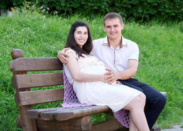 Zwangere vrouw en man op outdoor, gelukkig familie, paar in stadspark, zomerseizoen, groen gras en bomen — Stockfoto