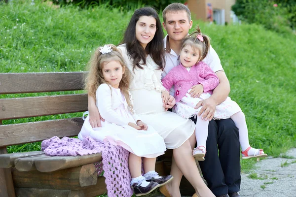 Rodina na venkovní, těhotná žena s dítětem a muž, městský park, letní sezóny, zelené trávy a stromů — Stock fotografie