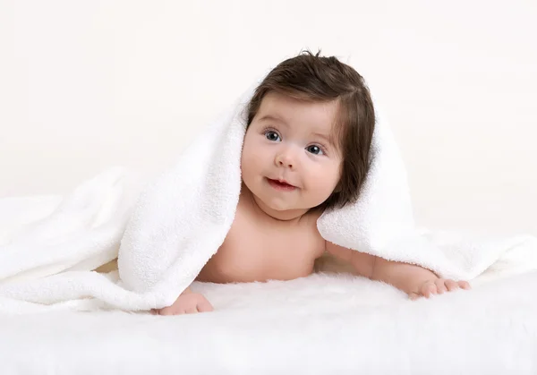 Baby portrét v posteli pod bílým ručníkem ve studiu — Stock fotografie