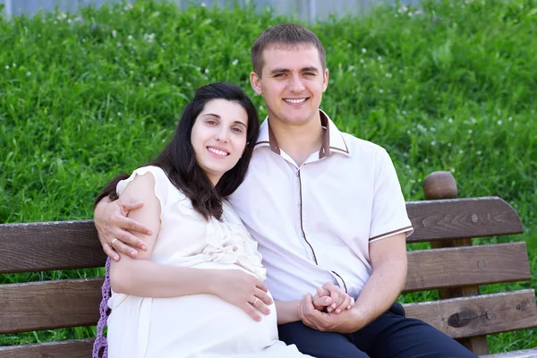 Těhotné ženě a manžel na venkovní, šťastná rodina, pár v městském parku, letní sezóny, zelené trávy a stromů — Stock fotografie