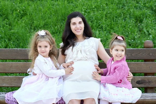 Família ao ar livre, mulher grávida com criança no parque da cidade, temporada de verão, grama verde e árvores — Fotografia de Stock