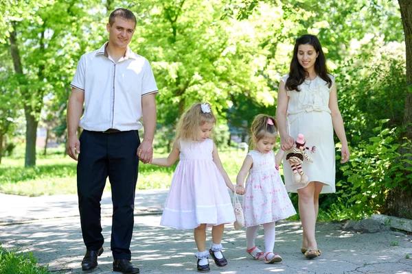 Família com criança e mulher grávida caminhar no parque da cidade de verão — Fotografia de Stock