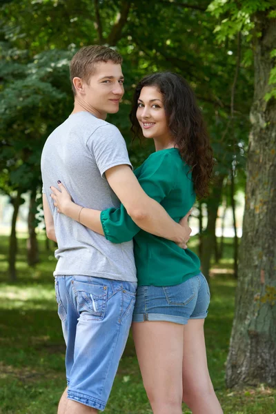 Романтична пара позує в міському парку, літній сезон, молодь позаду — стокове фото