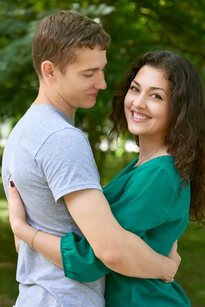 Романтическая пара позирует в городском парке, летний сезон, молодежь сзади — стоковое фото