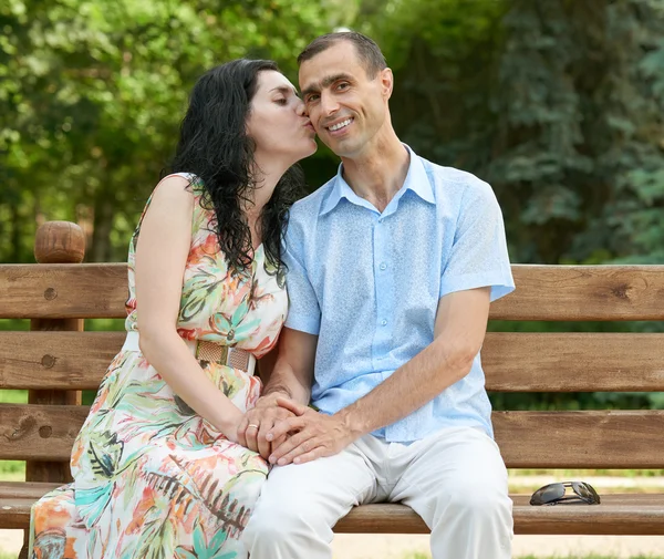 Romântico casal beijo no banco no parque da cidade, temporada de verão, adulto feliz pessoas homem e mulher — Fotografia de Stock
