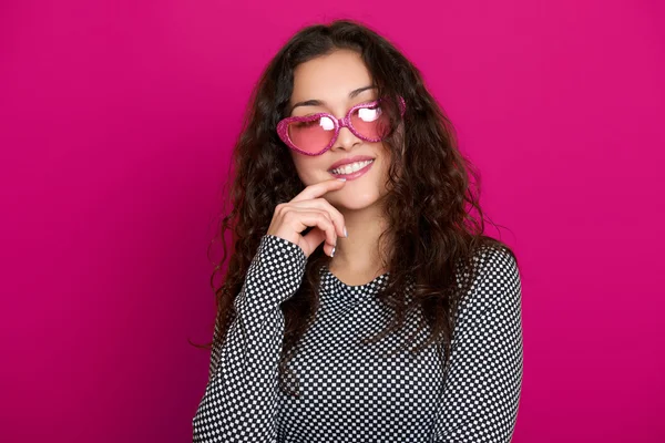 genç kadın güzel portre, poz pembe bir arka plan, uzun kıvırcık saç, kalp şeklinde, glamour kavramı güneş gözlüğü