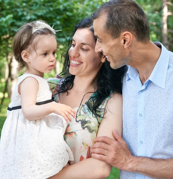 Rodinný portrét v létě městský park, rodiče s dítětem, letní sezóny, zelené trávy a stromů — Stock fotografie