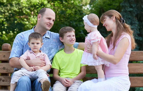 Glückliches Familienporträt im Freien, Gruppe von fünf Personen sitzt auf Holzbank im Stadtpark, Sommersaison, Kind und Eltern — Stockfoto