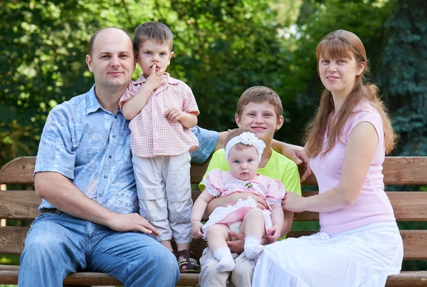 Gelukkig familieportret op outdoor, groep van vijf mensen zitten op houten bankje in stadspark, zomerseizoen, kind en ouder — Stockfoto