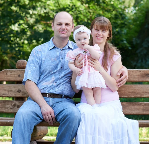 Glückliches Familienporträt im Freien, Gruppe von Baummenschen sitzt auf Holzbank im Stadtpark, Sommersaison, Kind und Eltern — Stockfoto