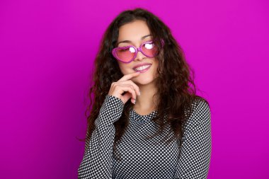 genç kadın güzel portre, poz mor arka plan, uzun kıvırcık saç, kalp şeklinde, glamour kavramı güneş gözlüğü