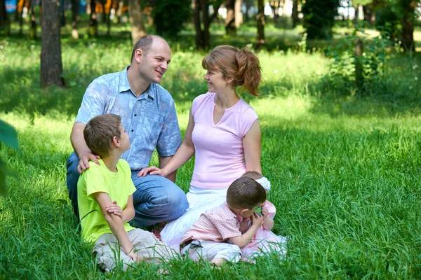 Retrato de família feliz ao ar livre, grupo de cinco pessoas sentam-se na grama no parque da cidade, temporada de verão, criança e pai — Fotografia de Stock