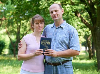erkek ve kadın bir İncil elini, mutlu bir aile ve din kavramı ile