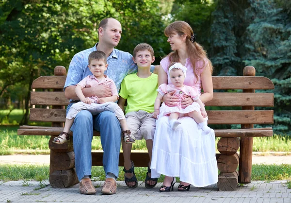 Gelukkig familieportret op outdoor, groep van vijf mensen zitten op houten bankje in stadspark, zomerseizoen, kind en ouder — Stockfoto