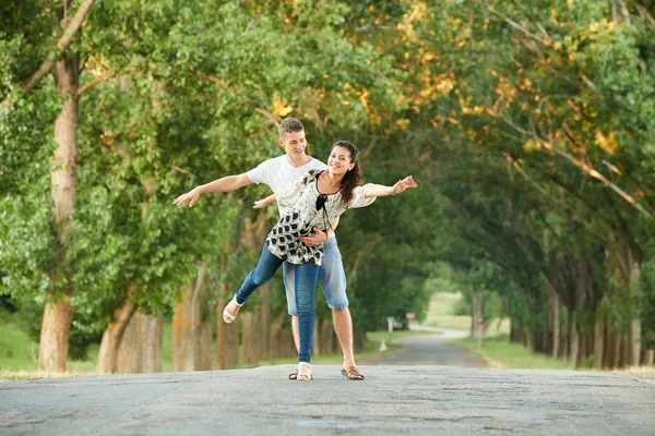 Feliz jovem casal andar na estrada do país ao ar livre, conceito de pessoas românticas, temporada de verão — Fotografia de Stock