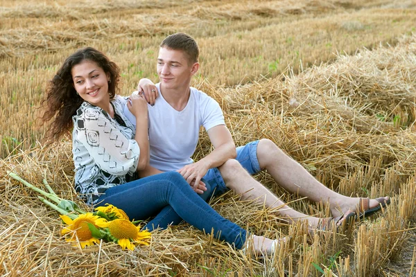 Feliz joven pareja sentarse en el campo de trigo por la noche, concepto de gente romántica, hermoso paisaje, temporada de verano — Foto de Stock