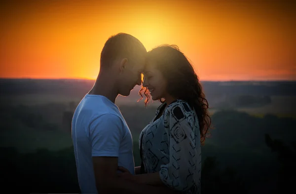 Pareja joven al atardecer en el fondo del cielo, concepto de amor, gente romántica — Foto de Stock