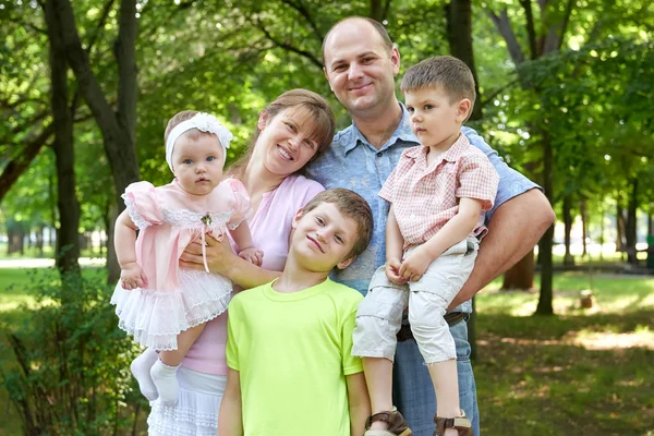 Ευτυχισμένη οικογένεια πορτρέτο σε δημοσια, πέντε άτομα που θέτουν σε πάρκο της πόλης, καλοκαιρινή σεζόν, παιδιού και η μητρική — Φωτογραφία Αρχείου