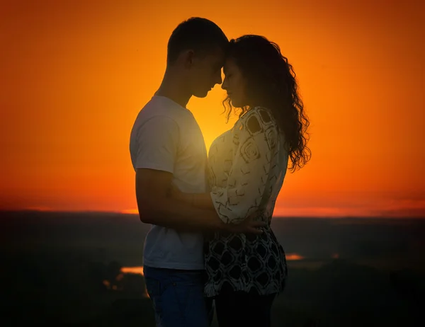 Pareja joven al atardecer en el fondo del cielo, concepto de amor, gente romántica — Foto de Stock