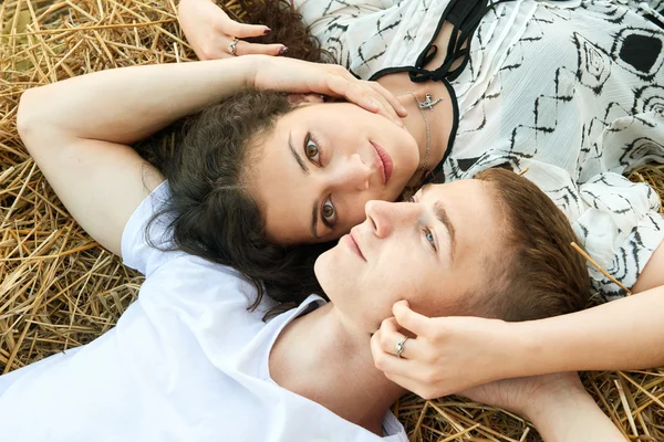 Счастливая молодая пара лежат в соломе, пшеничное поле вечером, романтическая концепция людей, красивый пейзаж, летний сезон — стоковое фото