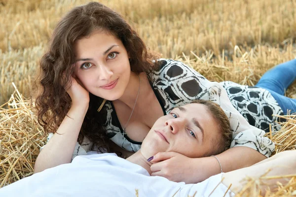 Счастливая молодая пара лежат в соломе, пшеничное поле вечером, романтическая концепция людей, красивый пейзаж, летний сезон — стоковое фото