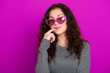 genç kadın güzel portre, poz mor arka plan, uzun kıvırcık saç, kalp şeklinde, glamour kavramı güneş gözlüğü