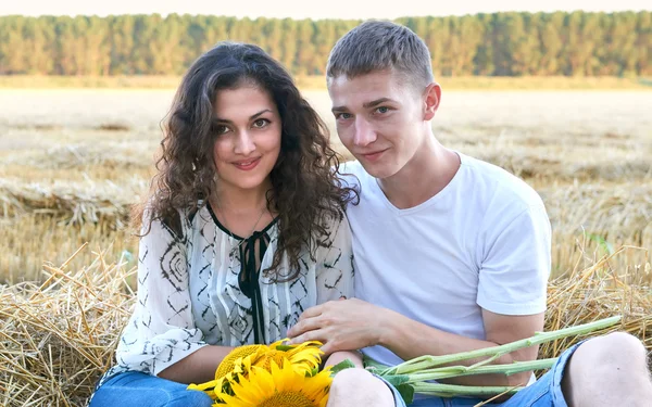 Feliz jovem casal sentar no campo de trigo à noite, conceito de pessoas românticas, bela paisagem, temporada de verão — Fotografia de Stock